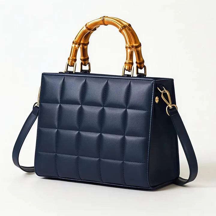 Blue quilted handbag with gold bamboo handle on a white background